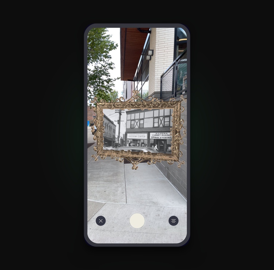 Looking Glass AR view: an ornate gold frame holds a historic black-and-white photo of the site, overlaid on the present-day street.